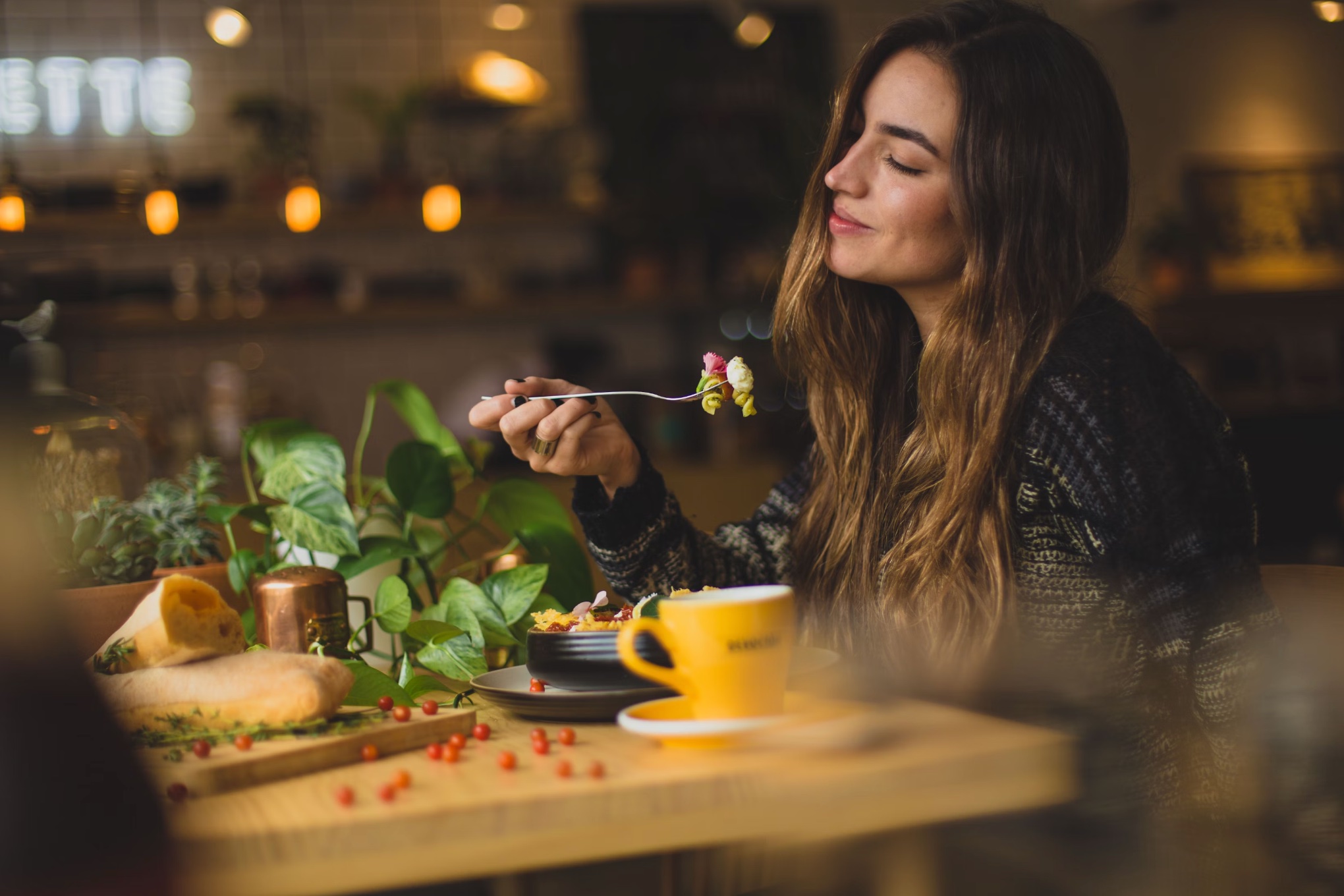 Woman eating a nourishing meal with leafy greens, seeds, and tea for hormone health